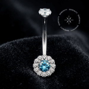 Piercing umbigo titânio em formato de flor de 12 pétalas cravejada com zircônias, haste curva com rosca interna, repousando suavemente sobre um tecido de cetim branco de alta opulência.
