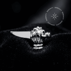 piercing titânio grau implante com design escultural de mão com adaga repousando suavemente sobre um tecido de cetim branco de alta opulência. piercing titânio grau implante