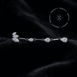 piercing titânio grau implante modelo topo pétalas max com longo pingente de 42mm cravejado em zircônias translúcidas, repousando suavemente sobre um tecido de cetim branco de alta opulência.
