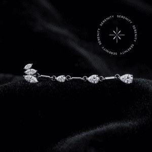 piercing titânio grau implante modelo topo pétalas max com longo pingente de 42mm cravejado em zircônias translúcidas, repousando suavemente sobre um tecido de cetim branco de alta opulência.
