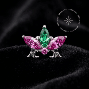 piercing titânio grau implante modelo topo 3 navetes cravejado com zircônias rosa e verde, repousando suavemente sobre um tecido de cetim branco de alta opulência.