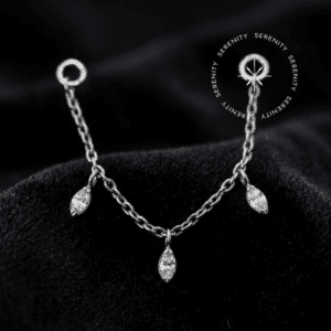 Piercing Corrente em Titânio ✦ ─────────── ✧ SERENITY ✧ ─────────── ✦ TN1648 - Corrente Cravejada Três Navetes - Titânio Grau Implante (ASTM F136) ✦ ─────────── ✧ SERENITY ✧ ─────────── ✦ 🛠️ ESPECIFICAÇÕES TÉCNICAS: Material Base: Titânio Grau Implante (ASTM F136) Mecanismo: Argolas de conexão nas extremidades (Compatível com hastes de até 1.6mm de espessura) Dimensões: Comprimento total de 40mm; espessura da malha de 0.6mm Gemas: 3x Zircônia Translúcida de Lapidação Premium (Corte Navete) Cor: Prateado natural do metal com o refulgir estrutural das zircônias translúcidas Venda: 1 Unidade (Hastes e topos de conexão vendidos separadamente) ✦ ─────────── ✧ SERENITY ✧ ─────────── ✦ O Piercing Corrente em Titânio foi projetado para elevar a estética do seu setup, transformando perfurações isoladas em uma composição de alto luxo limpo. A fluidez da malha de 0.6mm cria um caimento anatômico perfeito, enquanto as zircônias de lapidação navete atuam como pontos focais de altíssimo brilho, promovendo um contraste sofisticado contra a pele. Uma peça de presença marcante que desafia o comum através da sua arquitetura articulada. Por que o Piercing Corrente em Titânio é sinônimo de alta qualidade? Desenvolvida para máxima durabilidade e conforto contínuo, a malha desta corrente não retém resíduos e acompanha o movimento natural do corpo sem causar tensões nas perfurações. As zircônias em formato navete são cravadas com precisão cirúrgica, garantindo máxima refração de luz e uma fixação robusta que dispensa o uso de colas. É a fusão definitiva entre a vanguarda do design corporal e a engenharia de materiais de elite. Uma peça de tiragem restrita, esculpida com precisão cirúrgica. Eleve seu setup enquanto a curadoria atual está disponível. ✦ ─────────── ✧ SERENITY ✧ ─────────── ✦ Por que optar pelo Piercing Corrente em Titânio para o seu setup? Sua estrutura maleável abraça a anatomia com um caimento escultural, criando linhas de luz que conectam seus piercings de forma opulenta, luxuosa e absolutamente segura. ✦ ─────────── ✧ SERENITY ✧ ─────────── ✦ 📍 CURADORIA ANATÔMICA: (Nota de Estilo: Esta é uma joia de conexão. As argolas nas extremidades devem ser inseridas nas hastes dos piercings já existentes) Escafa/Flat e Hélix: Cria uma cortina de luz sofisticada e envolvente, interligando dois furos na curvatura superior da orelha com um volume estrutural marcante e elegante. Concha/Conch (Conexão ao Lóbulo ou Hélix): Transforma o Conch no centro de uma composição majestosa. A corrente envolve a lateral da orelha com fluidez, adicionando uma camada de alta joalheria que se adapta aos contornos auriculares perfeitamente. Lóbulo: Ideal para conectar perfurações duplas ou triplas no lóbulo, desenhando um caminho cintilante e dinâmico que exala autoridade estética. Nariz (Nostril Chain): Uma aplicação de vanguarda e altíssimo luxo. Conectando duas perfurações nas abas nasais, a corrente repousa sobre a ponte do nariz com uma simetria impecável, onde as zircônias navetes funcionam como um poderoso ponto de luz facial. ✦ ─────────── ✧ SERENITY ✧ ─────────── ✦ ⭐ DESTAQUES EXCLUSIVOS: Material de Elite: Forjada integralmente em Titânio Grau Implante (ASTM F136), entregando leveza absoluta e biocompatibilidade irrestrita. Engenharia de Encaixe: Malha de 0.6mm desenhada para não enroscar, com argolas terminais compatíveis de forma universal com hastes convencionais (1.0mm, 1.2mm e 1.6mm). Cravação de Alta Joalheria: Zircônias translúcidas presas por garras precisas que projetam a lapidação navete para maximizar a captura e o reflexo da luz ambiente. Polimento Espelhado: Acabamento premium impecável que realça a nobreza da coloração prateada natural, garantindo uma superfície perfeitamente lisa e livre de porosidade. ✦ ─────────── ✧ SERENITY ✧ ─────────── ✦ PUREZA ABSOLUTA E PERSONALIZAÇÃO - TITÂNIO GRAU IMPLANTE: Desfrute da coloração prateada natural do titânio em sua forma mais nobre, ou personalize sua joia! Oferecemos a opção de alterar a cor da sua peça através do processo de anodização. Essa tecnologia utiliza alta voltagem para reestruturar a superfície do metal, refletindo tons vibrantes de forma segura, sem o uso de tintas ou banhos químicos, mantendo 100% da pureza e da biocompatibilidade. ✦ ─────────── ✧ SERENITY ✧ ─────────── ✦ 💎 COMPROMISSO DE EXCELÊNCIA (CUIDADOS E GARANTIA): Selo de Garantia: 1 ano contra defeitos estruturais e de fabricação. Manutenção: Utilize apenas sabão neutro, água morna e secagem imediata. 🚨 ATENÇÃO: A troca por arrependimento só será aceita caso o lacre inviolável esteja intacto, garantindo a higiene