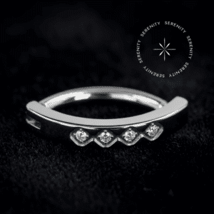 A fusão impecável entre a praticidade do design moderno e a exclusividade da alta joalheria.✦ ─────────── ✧ SERENITY ✧ ─────────── ✦TN1089 - Navel Clicker Cravejado 4 Gemas - Titânio Grau Implante (ASTM F136)✦ ─────────── ✧ SERENITY ✧ ─────────── ✦🛠️ ESPECIFICAÇÕES TÉCNICAS:AtributoDetalheMaterial BaseTitânio Grau Implante (ASTM F136)MecanismoClickerDimensõesHaste de 1.6 mm x 10 mm | Frente de 15 mm x 2.5 mmGemasZircônia Translúcida de Lapidação PremiumCorTitânio Natural e Zircônia TranslúcidaVendaUnidade✦ ─────────── ✧ SERENITY ✧ ─────────── ✦O Piercing de Umbigo Clicker em Titânio foi projetado para elevar a estética do seu setup. Uma joia que captura a essência do alto luxo limpo, destacando-se pelo alinhamento frontal de quatro zircônias primorosas e pelo sofisticado sistema de fechamento em arco, estruturado sob rigorosos padrões de alta joalheria. O acabamento impecável e o polimento magistral refletem uma aura de sofisticação ímpar, ideal para quem busca adornos de alto padrão com um visual minimalista, seguro e de fácil manuseio.Por que o Piercing de Umbigo Clicker em Titânio é sinônimo de alta qualidade?A excelência estrutural desta peça começa na pureza do seu metal biocompatível e se estende até o mecanismo articulado de fechamento (clicker), garantindo uma inserção completamente indolor, firme e que preserva o tecido cutâneo. A lapidação premium de suas gemas frontais foi meticulosamente executada para maximizar a refração da luz, criando um espetáculo visual de requinte atemporal e brilho contínuo. Uma peça de tiragem restrita, esculpida com precisão cirúrgica. Eleve seu setup enquanto a curadoria atual está disponível.✦ ─────────── ✧ SERENITY ✧ ─────────── ✦Por que optar pelo Piercing de Umbigo Clicker em Titânio para o seu setup?Seu design anatômico em argola articulada abraça a silhueta natural com perfeição, proporcionando um caimento luxuoso, estável e incrivelmente prático para o uso diário.✦ ─────────── ✧ SERENITY ✧ ─────────── ✦📍 CURADORIA ANATÔMICA:Umbigo: Esta peça foi engenheirada estritamente para a anatomia abdominal. O caimento da haste de 1.6 mm x 10 mm, aliado ao formato clicker com frente cravada de 15 mm, preenche o espaço do umbigo de forma ergonômica, segura e visualmente sofisticada. É estritamente proibido e não recomendado sugerir ou adaptar o uso desta joia para o nariz, orelha ou quaisquer outras regiões do corpo.✦ ─────────── ✧ SERENITY ✧ ─────────── ✦⭐ DESTAQUES EXCLUSIVOS:Material de Elite: Titânio Grau Implante puríssimo, levíssimo e completamente antialérgico.Engenharia de Encaixe: Sistema articulado clicker de altíssima precisão, garantindo fechamento seguro e contínuo.Cravação de Alta Joalheria: Quatro gemas perfeitamente alinhadas na face frontal, fixadas com segurança para brilho ininterrupto e durabilidade máxima.Polimento Espelhado: Superfície pristina que realça a nobreza e facilita a perfeita higienização do metal.✦ ─────────── ✧ SERENITY ✧ ─────────── ✦PUREZA ABSOLUTA E PERSONALIZAÇÃO - TITÂNIO GRAU IMPLANTE: Desfrute da coloração prateada natural do titânio em sua forma mais nobre, ou personalize sua joia! Oferecemos a opção de alterar a cor da sua peça através do processo de anodização. Essa tecnologia utiliza alta voltagem para reestruturar a superfície do metal, refletindo tons vibrantes de forma segura, sem o uso de tintas ou banhos químicos, mantendo 100% da pureza e da biocompatibilidade.✦ ─────────── ✧ SERENITY ✧ ─────────── ✦💎 COMPROMISSO DE EXCELÊNCIA (CUIDADOS E GARANTIA):Selo de Garantia: 1 ano contra defeitos estruturais e de fabricação.Manutenção: Utilize apenas sabão neutro, água morna e secagem imediata.🚨 ATENÇÃO: A troca por arrependimento só será aceita caso o lacre inviolável esteja intacto, garantindo a higiene.