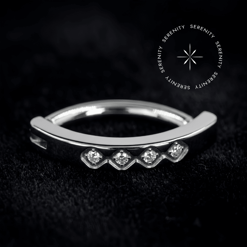 A fusão impecável entre a praticidade do design moderno e a exclusividade da alta joalheria.✦ ─────────── ✧ SERENITY ✧ ─────────── ✦TN1089 - Navel Clicker Cravejado 4 Gemas - Titânio Grau Implante (ASTM F136)✦ ─────────── ✧ SERENITY ✧ ─────────── ✦🛠️ ESPECIFICAÇÕES TÉCNICAS:AtributoDetalheMaterial BaseTitânio Grau Implante (ASTM F136)MecanismoClickerDimensõesHaste de 1.6 mm x 10 mm | Frente de 15 mm x 2.5 mmGemasZircônia Translúcida de Lapidação PremiumCorTitânio Natural e Zircônia TranslúcidaVendaUnidade✦ ─────────── ✧ SERENITY ✧ ─────────── ✦O Piercing de Umbigo Clicker em Titânio foi projetado para elevar a estética do seu setup. Uma joia que captura a essência do alto luxo limpo, destacando-se pelo alinhamento frontal de quatro zircônias primorosas e pelo sofisticado sistema de fechamento em arco, estruturado sob rigorosos padrões de alta joalheria. O acabamento impecável e o polimento magistral refletem uma aura de sofisticação ímpar, ideal para quem busca adornos de alto padrão com um visual minimalista, seguro e de fácil manuseio.Por que o Piercing de Umbigo Clicker em Titânio é sinônimo de alta qualidade?A excelência estrutural desta peça começa na pureza do seu metal biocompatível e se estende até o mecanismo articulado de fechamento (clicker), garantindo uma inserção completamente indolor, firme e que preserva o tecido cutâneo. A lapidação premium de suas gemas frontais foi meticulosamente executada para maximizar a refração da luz, criando um espetáculo visual de requinte atemporal e brilho contínuo. Uma peça de tiragem restrita, esculpida com precisão cirúrgica. Eleve seu setup enquanto a curadoria atual está disponível.✦ ─────────── ✧ SERENITY ✧ ─────────── ✦Por que optar pelo Piercing de Umbigo Clicker em Titânio para o seu setup?Seu design anatômico em argola articulada abraça a silhueta natural com perfeição, proporcionando um caimento luxuoso, estável e incrivelmente prático para o uso diário.✦ ─────────── ✧ SERENITY ✧ ─────────── ✦📍 CURADORIA ANATÔMICA:Umbigo: Esta peça foi engenheirada estritamente para a anatomia abdominal. O caimento da haste de 1.6 mm x 10 mm, aliado ao formato clicker com frente cravada de 15 mm, preenche o espaço do umbigo de forma ergonômica, segura e visualmente sofisticada. É estritamente proibido e não recomendado sugerir ou adaptar o uso desta joia para o nariz, orelha ou quaisquer outras regiões do corpo.✦ ─────────── ✧ SERENITY ✧ ─────────── ✦⭐ DESTAQUES EXCLUSIVOS:Material de Elite: Titânio Grau Implante puríssimo, levíssimo e completamente antialérgico.Engenharia de Encaixe: Sistema articulado clicker de altíssima precisão, garantindo fechamento seguro e contínuo.Cravação de Alta Joalheria: Quatro gemas perfeitamente alinhadas na face frontal, fixadas com segurança para brilho ininterrupto e durabilidade máxima.Polimento Espelhado: Superfície pristina que realça a nobreza e facilita a perfeita higienização do metal.✦ ─────────── ✧ SERENITY ✧ ─────────── ✦PUREZA ABSOLUTA E PERSONALIZAÇÃO - TITÂNIO GRAU IMPLANTE: Desfrute da coloração prateada natural do titânio em sua forma mais nobre, ou personalize sua joia! Oferecemos a opção de alterar a cor da sua peça através do processo de anodização. Essa tecnologia utiliza alta voltagem para reestruturar a superfície do metal, refletindo tons vibrantes de forma segura, sem o uso de tintas ou banhos químicos, mantendo 100% da pureza e da biocompatibilidade.✦ ─────────── ✧ SERENITY ✧ ─────────── ✦💎 COMPROMISSO DE EXCELÊNCIA (CUIDADOS E GARANTIA):Selo de Garantia: 1 ano contra defeitos estruturais e de fabricação.Manutenção: Utilize apenas sabão neutro, água morna e secagem imediata.🚨 ATENÇÃO: A troca por arrependimento só será aceita caso o lacre inviolável esteja intacto, garantindo a higiene.