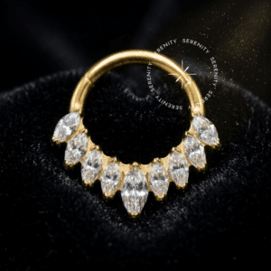 Argola Frontal 9 Navetes utilizada como piercing, forjada em Titânio Revestido de Ouro 18k com coroa de nove zircônias cristais transparentes em corte alongado marquise, fotografada em fundo claro.