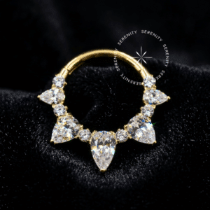Argola Frontal Coroa Navetes utilizada como piercing, forjada em Titânio Revestido de Ouro 18k com zircônias cristais transparentes em corte alongado marquise, fotografada em fundo claro.
