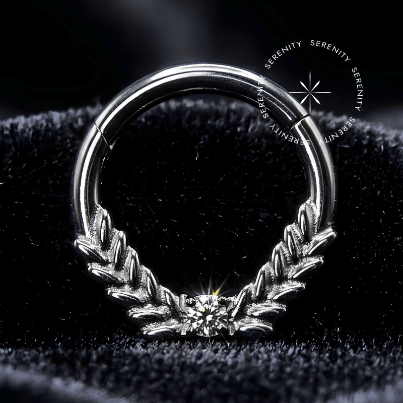 Argola Septo Titânio com design de ramos de louro em estilo grego, textura detalhada e cravação frontal de zircônias premium translúcidas, encaixe articulado tipo clicker, ideal para perfurações de septo e daith.