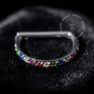 Argola Clicker Titânio em formato D-Ring, cravejada com Zircônias Premium arco-íris na borda externa frontal, com sistema de encaixe em haste reta, ideal para perfurações de septo e daith, como detalhado no arquivo image_ab554d.png.
