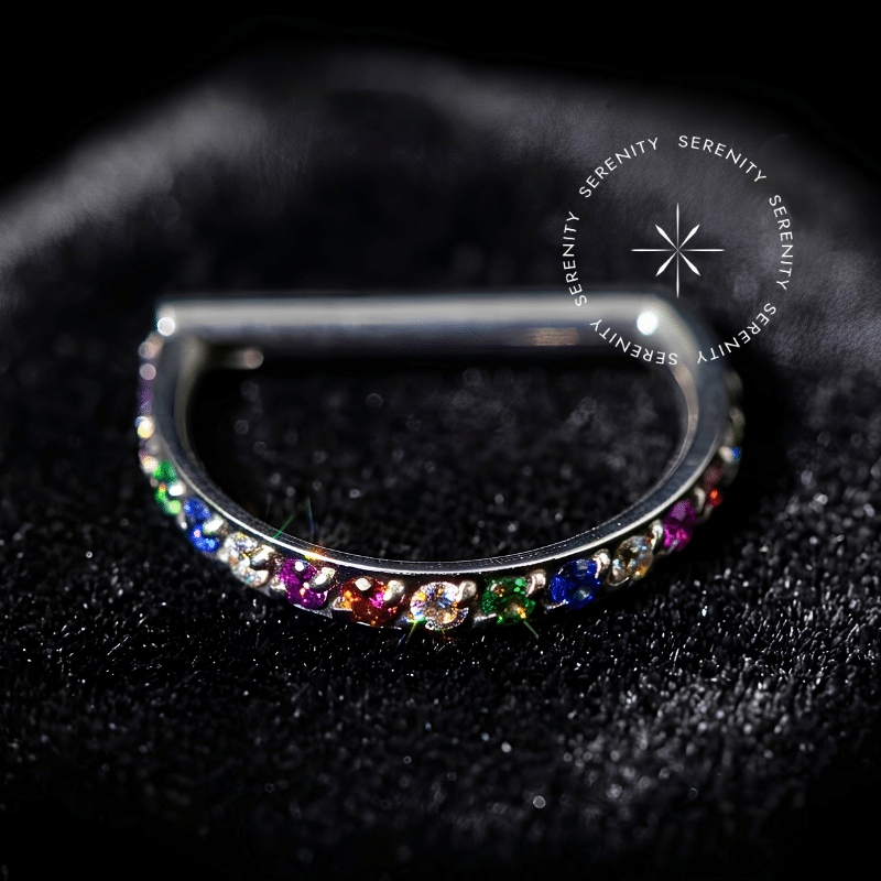 Argola Clicker Titânio em formato D-Ring, cravejada com Zircônias Premium arco-íris na borda externa frontal, com sistema de encaixe em haste reta, ideal para perfurações de septo e daith, como detalhado no arquivo image_ab554d.png.