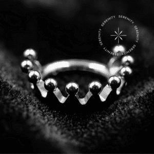 Argola Helix Titânio com design lateral em formato de coroa lisa e estruturada, polimento espelhado intenso, fecho clicker articulado anatômico, repousando sobre um belíssimo e suntuoso fundo de cetim, ideal para uso na lateral da cartilagem da orelha.