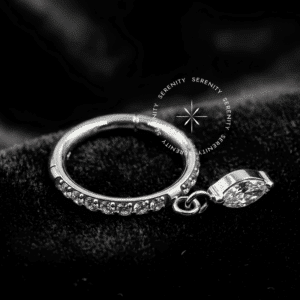 Texto Alternativo (Alt Text): Argola Click Titânio com cravação lateral de zircônias premium e charm pingente dinâmico de lapidação navete, sistema de encaixe articulado em clique de precisão, ideal para protagonismo com balanço luxuoso no lóbulo e hélix.