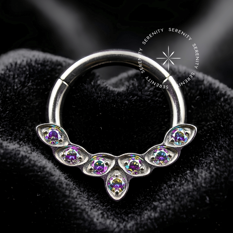 Piercing septo titânio TN531 apresentando modelo de argola segmento frontal cravejada com fileira de sete zircônias premium em corte brilhante ascendente, confeccionado em titânio grau implante hipoalergênico com dobradiça clicker para aplicação em septo e daith.