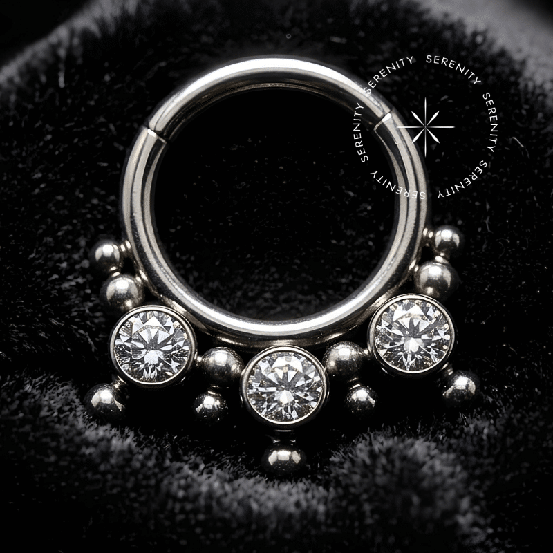 argola septo titânio com design frontal de três esferas cravejadas com zircônias cúbicas brilhantes, fecho clicker articulado e acabamento polido de alto brilho para aplicação em septo ou daith.
