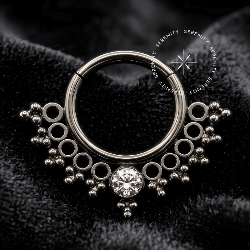 argola septo titânio com design rendado em estilo indiano e gema central em formato de gota de zircônia cúbica brilhante, fecho articulado clicker em titânio de grau implante.