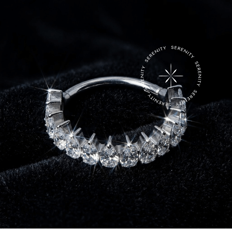 Piercing Titânio Grau Implante modelo argola com design de coroa cravejada de pedras de zircônia premium, sistema de fechamento clicker, acabamento prateado brilhante, ideal para septo e daith.