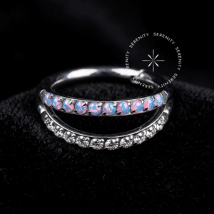 Argola Dupla Titânio com design de duas fileiras, apresentando cravação lateral de Opala Sintética iridescente azulada e Zircônia Premium transparente, sistema de fecho clicker articulado, ideal para perfurações de cartilagem como helix e conch.