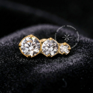 Piercing Titânio Dourado com design de cluster composto por três zircônias cristal em tamanhos graduais, acabamento espelhado em ouro 18k, encaixe push pin para hastes labret, focado em alta joalheria para tragus, flat e hélix.