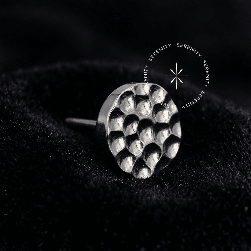 Piercing Titânio Cartilagem com design de topo disco martelado e textura facetada reflexiva prateada, dotado de pino fino para encaixe de pressão push pin, perfeito para atualização de setup na orelha.