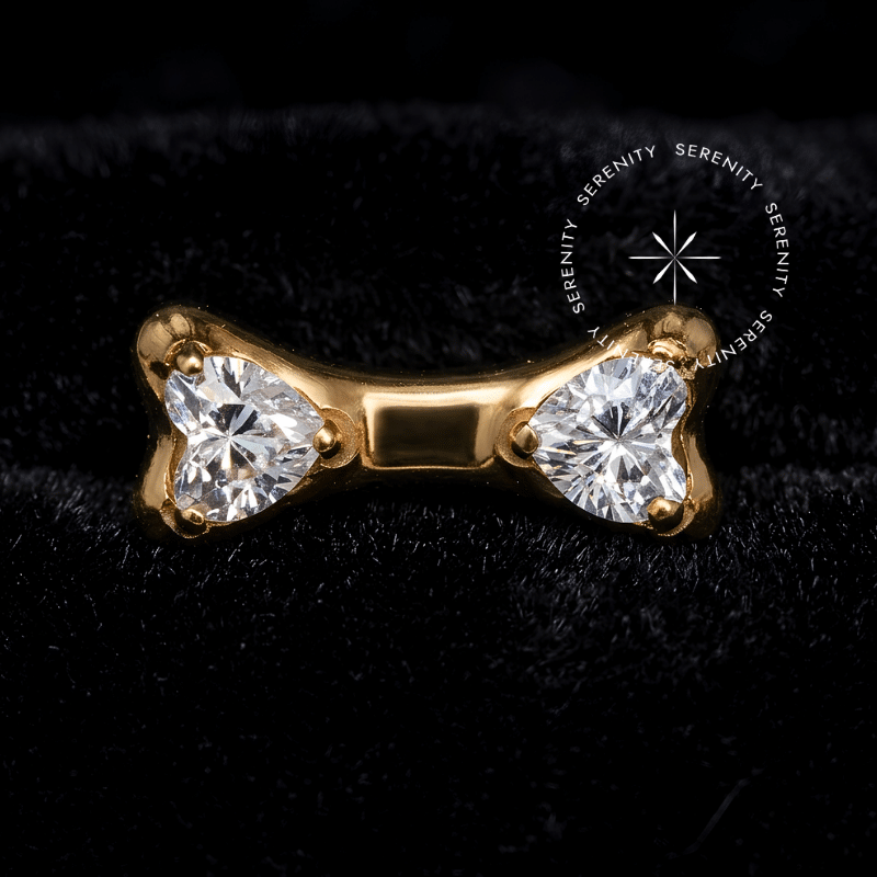 Piercing Titânio Dourado em formato de ossinho delicado com superfície ultra polida, cravejado com duas Zircônias Premium Translúcidas, exibindo pino de rosca interna de 0.9mm. Peça de luxo fotografada em escala macro, ideal para curadorias de hélix e cartilagem.