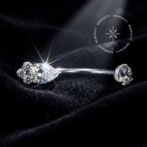 Piercing Umbigo Titânio Grau Implante com haste curva apresentando topo com três zircônias premium em formato trinity e base em gema majestosa formato gota translúcido, encaixe em pino de rosca interna atraumática, repousando e refletindo seu brilho intenso sobre um tecido de cetim liso, brilhante e branco puro, ideal para perfuração navel em composições de alta joalheria corporal.