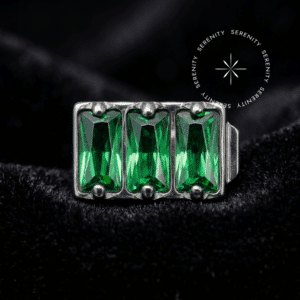 Piercing Titânio Grau Implante com design retangular em formato de bateria contendo três zircônias premium verde imperial, sistema de pino para rosca interna atraumática, refletindo sua cor rica sobre um tecido de cetim liso, brilhante e branco puro, ideal para conch e flat em curadorias de alta joalheria.