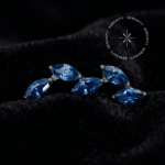 piercing rosca interna titânio com design em cluster curvo, formando um agrupamento de 5 zircônias premium na cor azul oceano com lapidação navete. Pinos em rosca de 0.9mm perfeitamente compatíveis com haste de 1.2mm, ideal para preenchimento de conch e flat auricular.