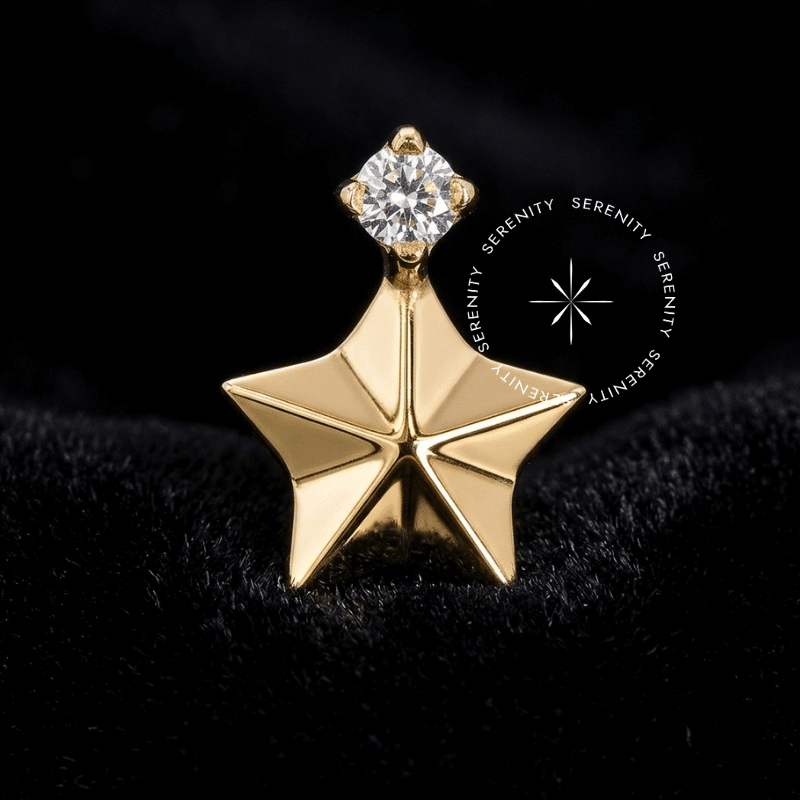 Piercing Titânio Dourado em formato de estrela meticulosamente facetada em 3D, encimada por uma Zircônia Premium Translúcida de lapidação circular brilhante. Superfície do metal ultra polida e cravamento de altíssima precisão. Fotografia macro de luxo focada nas áreas de alto contraste e refração luminosa, ideal para curadorias imponentes de hélix e conch.
