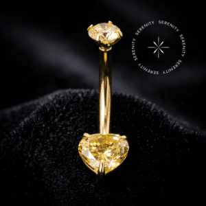 piercing umbigo titânio dourado de luxo em formato navel curvo ergonômico, cravejado na base inferior com uma majestosa Zircônia Premium Imperial na cor amarelo dourado com lapidação coração e ponto de luz superior de 4.0 mm, confeccionado em Titânio Grau Implante ASTM F136 com acabamento em ouro 18k via tecnologia PVD, sistema de rosca interna altamente seguro e hipoalergênico ideal para perfurações abdominais.