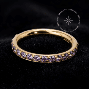 Argola cravejada ouro 18k com mecanismo clicker articulado, inteiramente ornamentada na borda externa com Zircônias Premium na cor Violeta Imperial sobre metal dourado, da exclusiva marca Serenity.