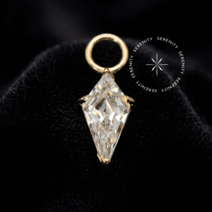 piercing titânio dourado em formato de pingente losango (8.5mm x 3.5mm), cravejado com uma única Zircônia Premium Radiante lapidada geometricamente, argola superior lisa para passagem fluida e movimento em perfurações de hélix e lóbulo em alta joalheria.