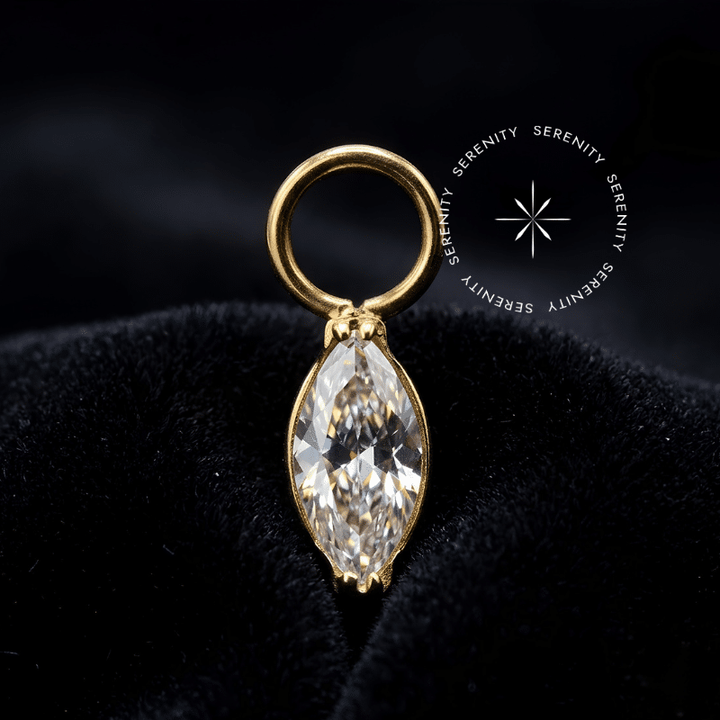 Pingente titânio dourado modelo navete delicada de 4.5mm em titânio grau implante ASTM F136 revestido em ouro 18k PVD com zircônia premium em lapidação marquise nas variações translúcida ou esmeraldina, argola de conexão superior para brincos e piercings de lóbulo, tragus ou hélix.