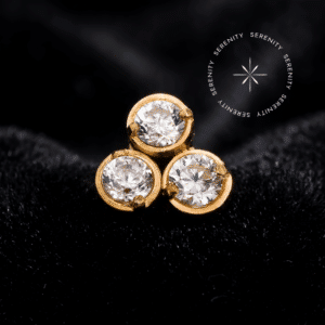 Fotografia macro do Topo Trinity Circular Cravejado em Titânio Revestido de Ouro 18k com zircônias translúcidas de lapidação premium refletindo a luz intensamente.