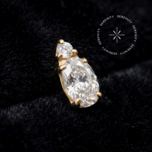 Topo Tragus Titânio Dourado com Zircônia Premium oval em lapidação translúcida majestic, acabamento espelhado em PVD dourado sobre haste com rosca interna, fotografado sobre cetim branco.