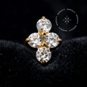 piercing titânio dourado exibindo um requintado design mini clover com quatro pedras cravadas de Zircônia Premium Translúcido Majestic, pino de rosca interna de 0.9mm polido e perfeito, forjado em titânio revestido em ouro 18k PVD repousando elegantemente sobre fundo suave, ideal para protagonizar perfurações no tragus, hélix e flat cartilaginoso.