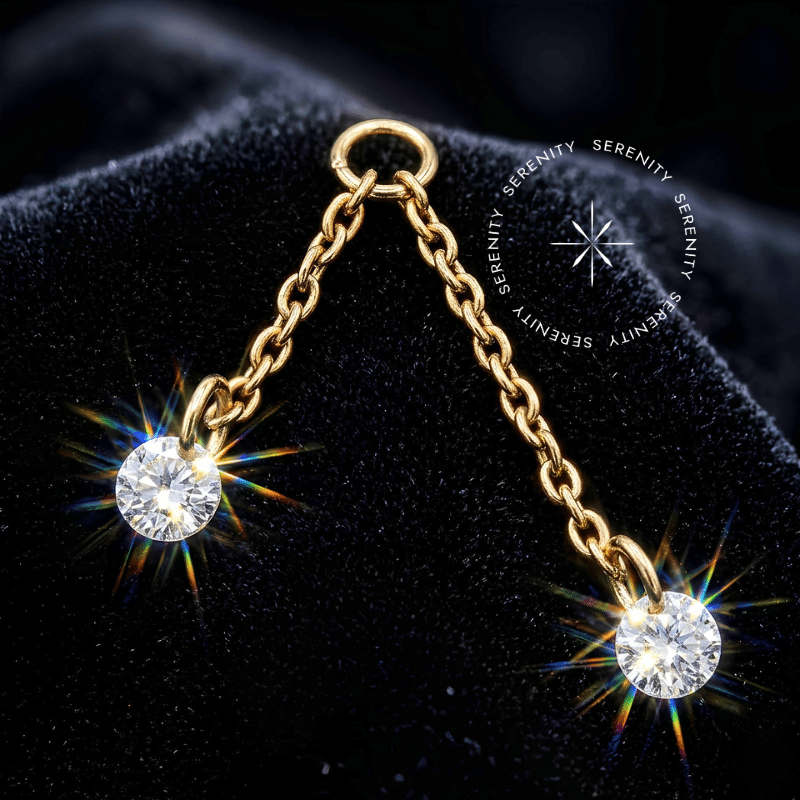 Pingente titânio dourado com correntes duplas venezianas de 9.5mm e 16mm em titânio grau implante ASTM F136 revestido em ouro 18k PVD e duas zircônias premium radiantes de 2mm nas pontas, argola de passagem superior para conexão em brincos e piercings de lóbulo, tragus ou hélix.