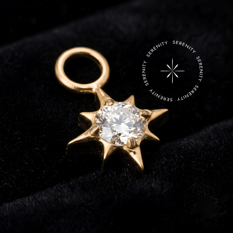 Pingente Titânio Dourado em formato de estrela cravejada com Zircônia Premium Translúcida central, elo superior liso para encaixe em argolas e labrets, ideal para composições luxuosas na orelha.