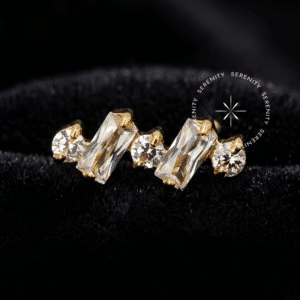 Piercing Titânio Dourado topo cluster com lapidação mista de duas Zircônias Premium baguete e três brilhantes claras, sistema de encaixe por rosca interna usinado em titânio grau implante revestido de ouro 18k para perfurações de cartilagem e tragus.