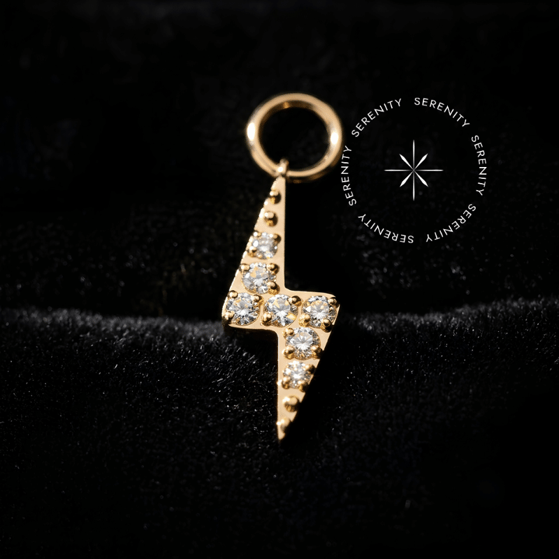 Pingente titânio dourado modelo raio cravejado de 9.5mm x 3.4mm em titânio grau implante ASTM F136 revestido em ouro 18k PVD com cravação pavé de zircônias premium radiantes, argola contínua de passagem para conexão em brincos e piercings de lóbulo, tragus ou hélix.