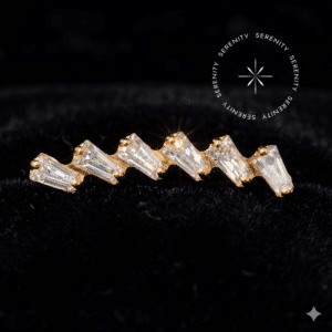 Piercing titânio dourado com design em formato de cluster alongado curvo, cravejado com seis pedras translúcidas de corte baguette, sistema de pino para rosca interna, ideal para perfurações na hélice, conch e lóbul