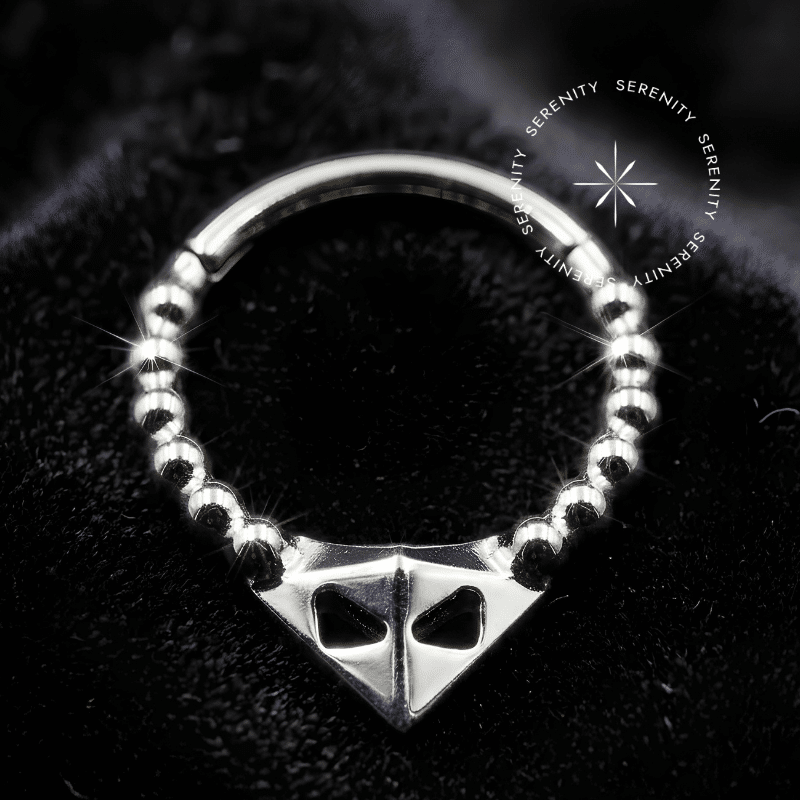 Argola Septo Titânio com design frontal triangular ornamentado, acabamento polido espelhado, fecho tipo clicker articulado, ideal para aplicação elegante em septo e daith.