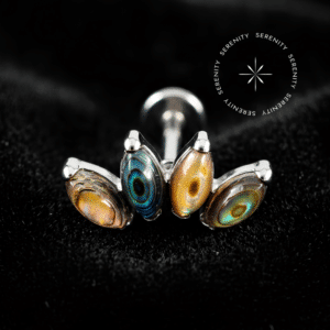 piercing titânio grau implante com design cluster de 11mm e quatro autênticas pedras naturais abalone repousando suavemente sobre um tecido de cetim branco de alta opulência.