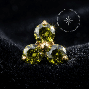Topo Trinity Titânio Dourado apresentando design de três pontas com zircônias de lapidação premium na cor verde peridoto, destacando o encaixe push pin e o brilho do PVD Gold.
