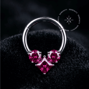 piercing septo titânio com design de argola clicker adornado por três zircônias rosa pink de lapidação premium, repousando suavemente sobre um tecido de cetim branco de alta opulência.
