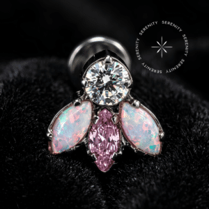 piercing titânio grau implante com design em cluster adornado por zircônia translúcida superior, zircônia rosa central e opalas laterais com tons lilás, repousando suavemente sobre um tecido de cetim branco de alta opulência.
