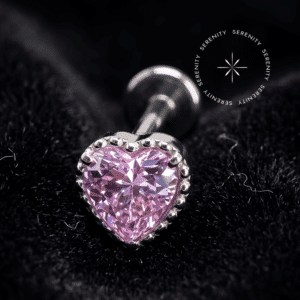 piercing titânio grau implante com design em formato de coração adornado por uma zircônia rosa de lapidação premium, repousando suavemente sobre um tecido de cetim branco de alta opulência.