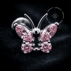 piercing titânio grau implante com design de borboleta adornado por quatro zircônias rosas, repousando suavemente sobre um tecido de cetim branco de alta opulência.
