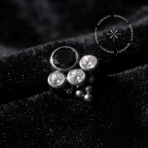 Piercing Labret topo big stone esferas cravejado com gemas translúcidas e opala em titânio grau implante natural repousando suavemente sobre um tecido de cetim branco de alta opulência.