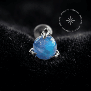 Topo Garras Cravejado com Opala Azul Cultivada em Laboratório repousando suavemente sobre um tecido de cetim branco de alta opulência, evidenciando os reflexos rosa e verde da gema.