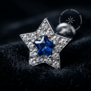 Topo Estrela Cravejado em Titânio Grau Implante repousando suavemente sobre um tecido de cetim branco de alta opulência, evidenciando a zircônia azul central e o halo translúcido cintilante.