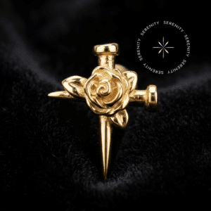 piercing titânio dourado com design de cruz de pregos e rosa em alto relevo repousando suavemente sobre um tecido de cetim branco de alta opulência.
